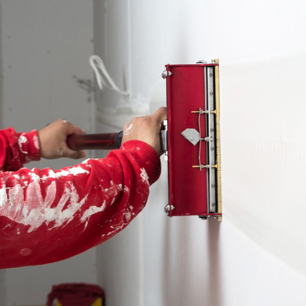 Person running a red Level 5 flat box attached to a Level 5 extenedable flat box handle across an unifinished wall joint